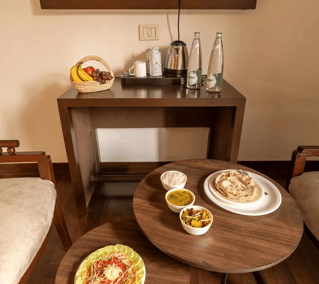 A dining setup with multiple Indian dishes placed on a round table with two chairs - Lime Boutique Bed & Breakfast | Nehru Place Metro